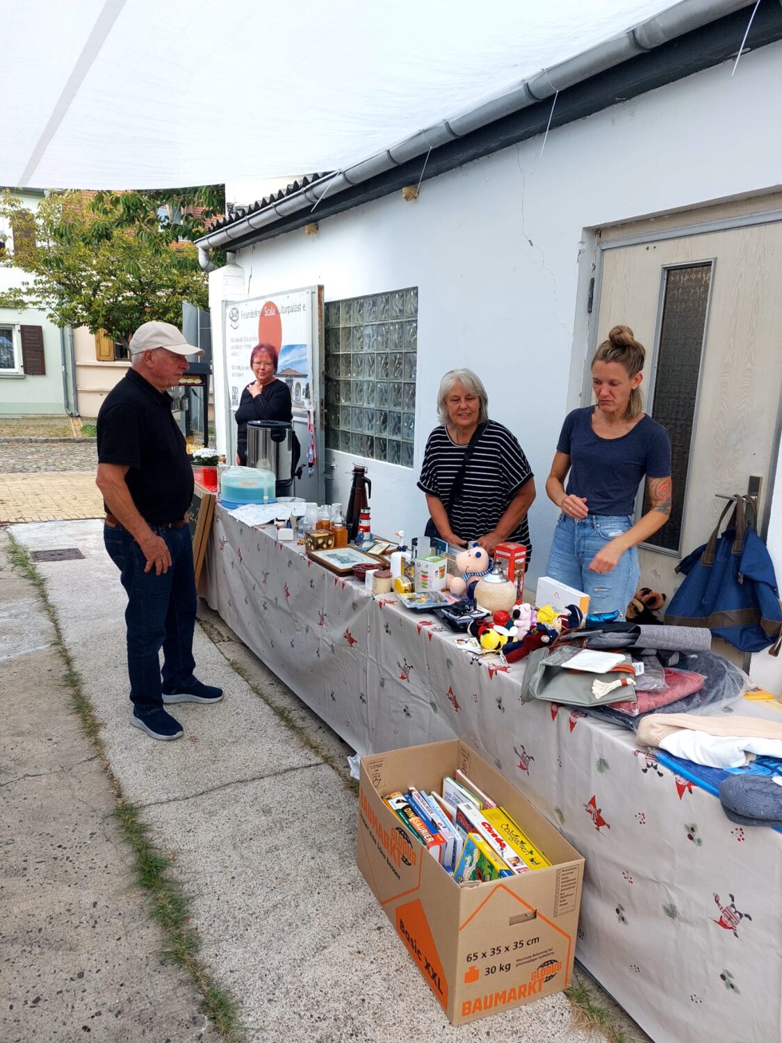 Flohmarktstand in Richtung Hofausgang mit Bücher- und Spielekiste davor