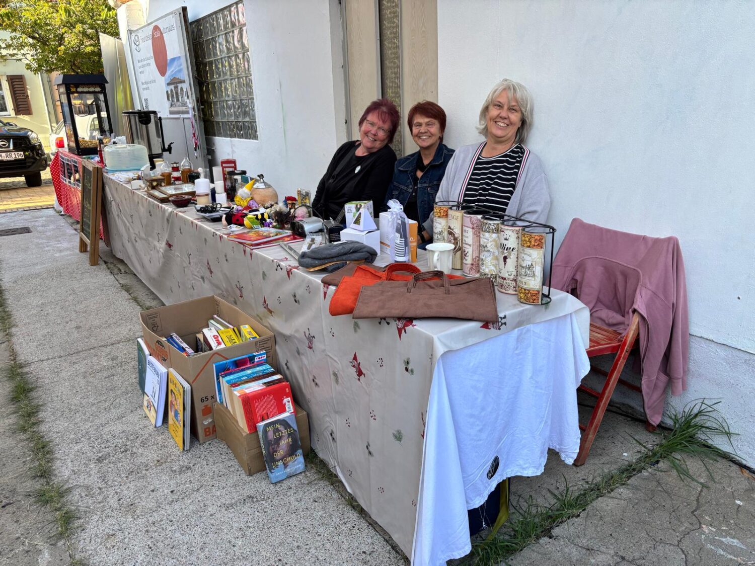Britta, Manu und Inge sitzend hinterm Flohmarktstand