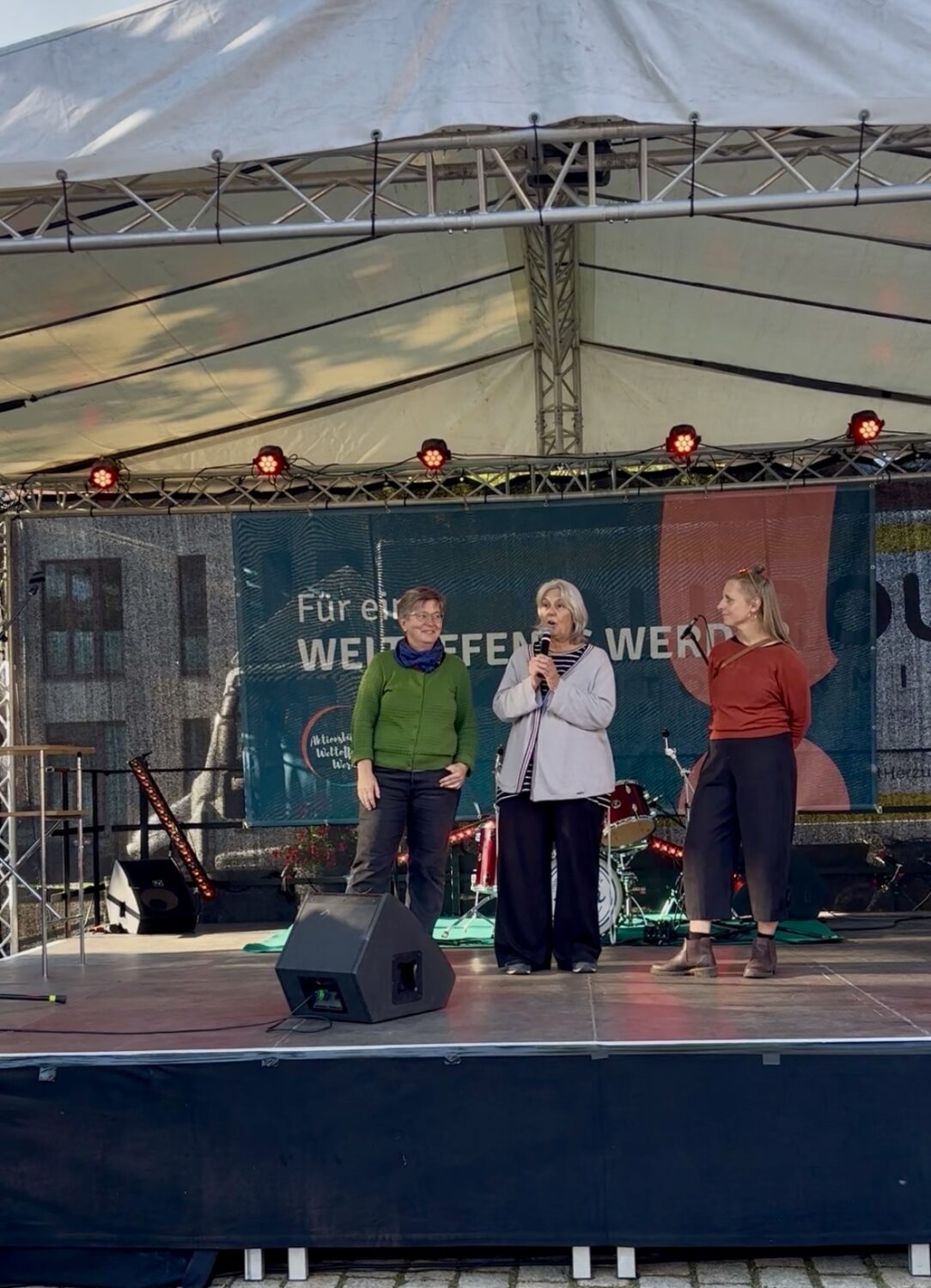 Haike und die Moderatorin hören Inge auf der Festival-Bühne zu