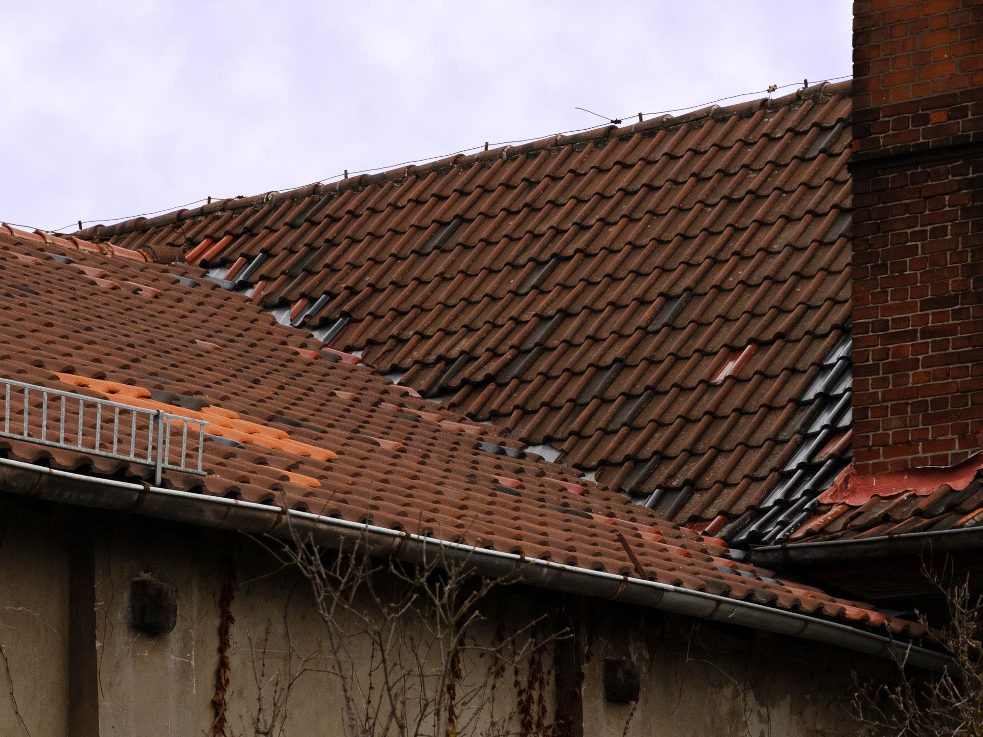 Dachdeckung mit Flicken sowie alter Schornstein